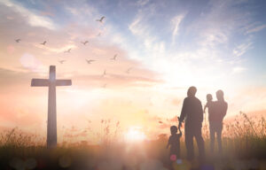 Family on the way to church. Family looking at the cross in a field. The sky is blue and doves are flying above the cross.